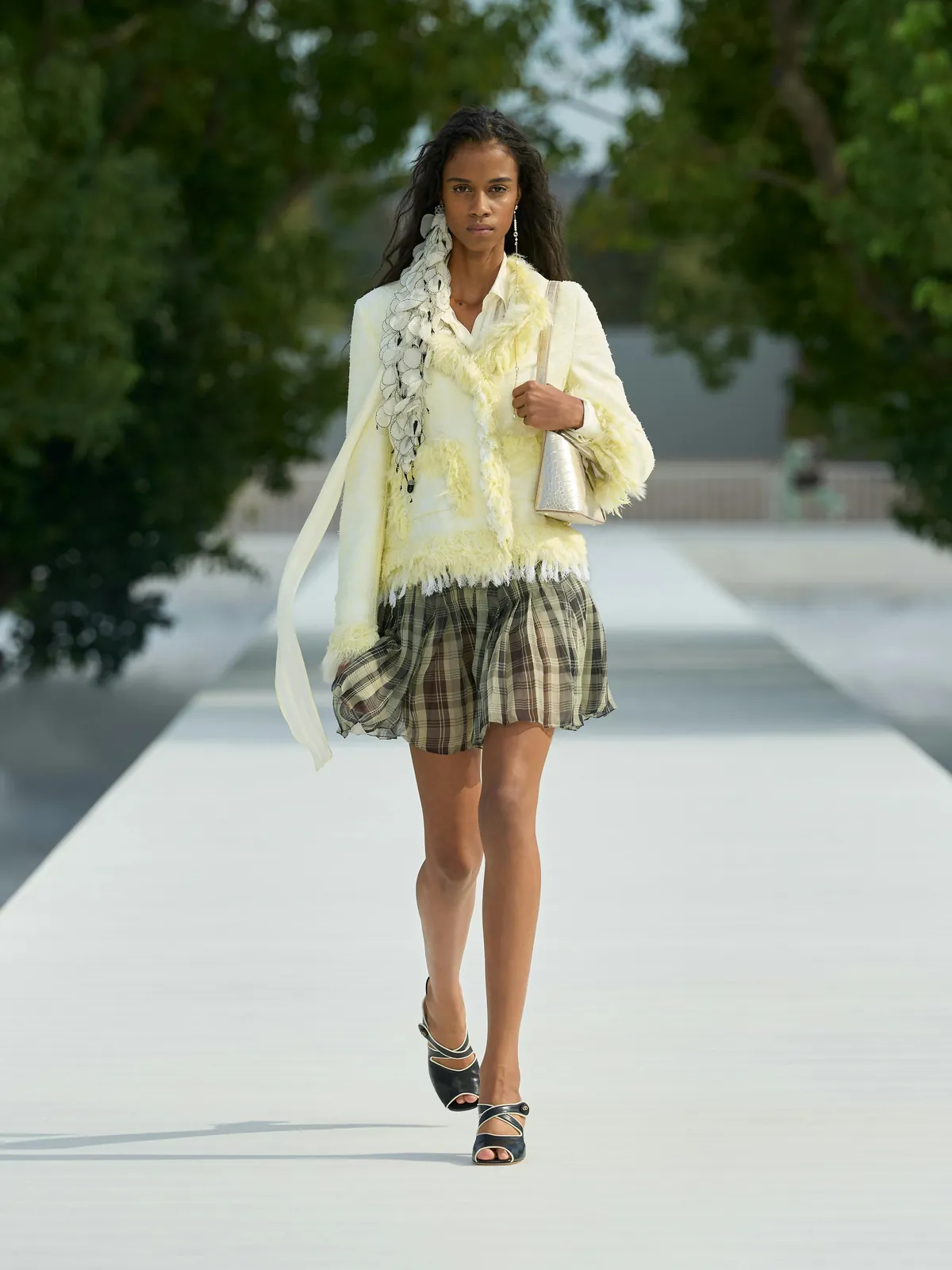 Dior Summer 2027 look 3: chaqueta amarillo pálido con flecos, pañuelo con volantes y minifalda de cuadros