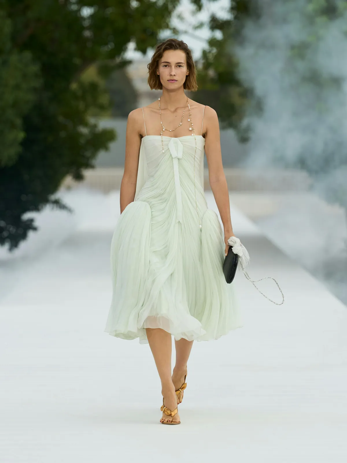 Dior Summer 2027 look 47: vestido plisado y translúcido en verde pálido con collares largos