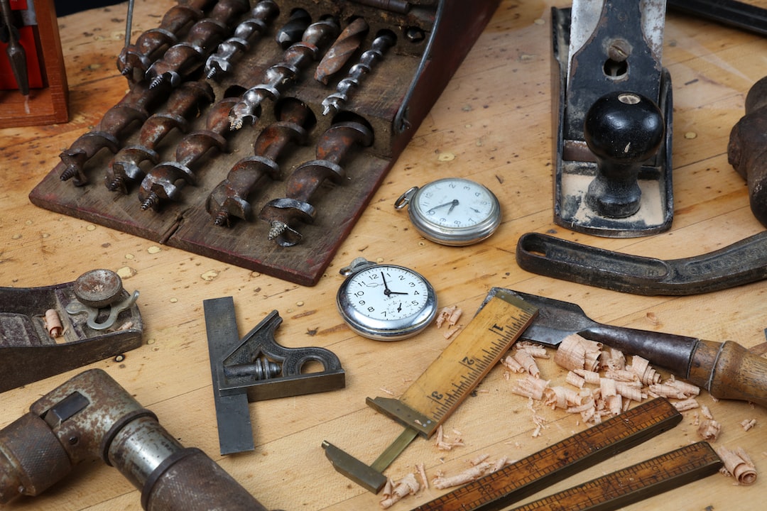 Un banco de trabajo de madera con herramientas vintage para trabajar la madera, dos cronómetros, brocas, una escuadra, una regla, virutas de madera y un cepillo de mano: un espacio artesanal donde la artesanía se une al lujo.